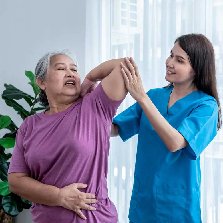 A caregiver doing arm exercise for elderly woman at home to treat osteoarthritis and nerve pain in the hand