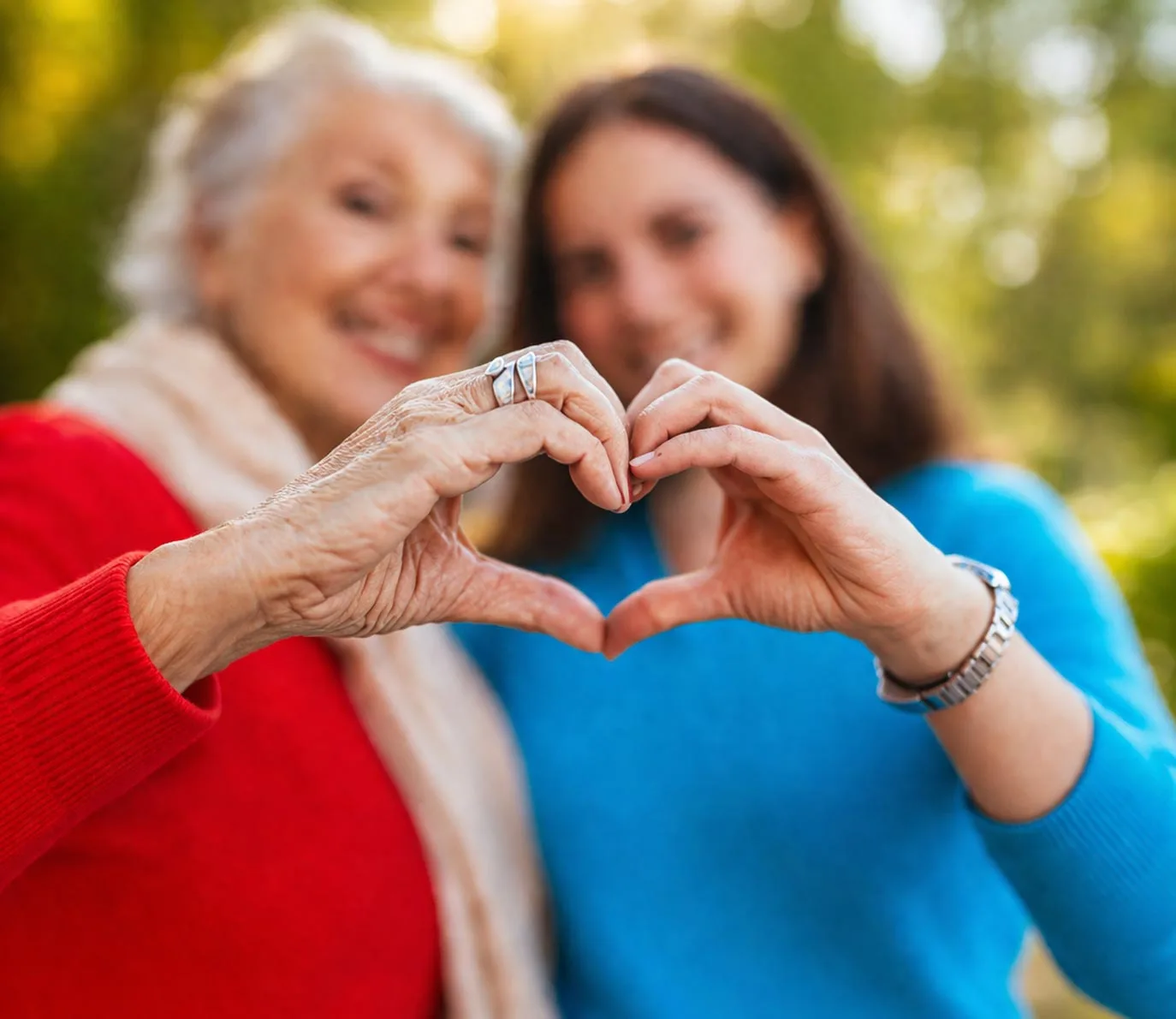 Caregiver and senior forming heart hands outdoors, symbolizing compassionate in-home care in Philadelphia